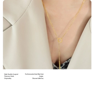 Detailed view of 18K gold titanium steel necklace with tassel and round charm on model