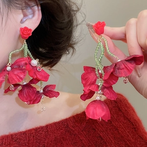 Detail of red fabric flower earrings with green beads and crystal tassels on model