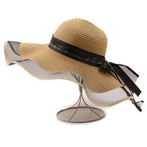 Détail d'un chapeau de soleil en paille avec bord en tulle noir et ruban à nœud doré