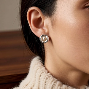 Primer plano detallado de elegantes pendientes de perlas plateadas irregulares en un modelo