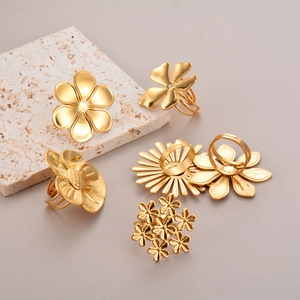 Close-up of elegant gold flower rings collection on a natural travertine stone stand