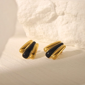 Macro detail of 18k gold plated shell-shaped earrings with striped black enamel accents