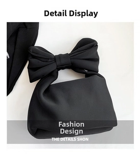 Detailed close-up of large decorative bow handle on minimalist black tote bag
