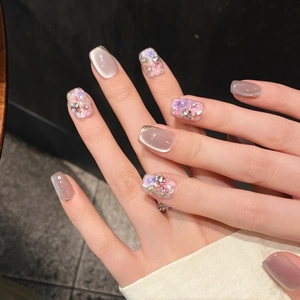 Detailansicht handgefertigter Kunstnägel mit Cat-Eye-Effekt, Trockenblumen und Strasssteinen