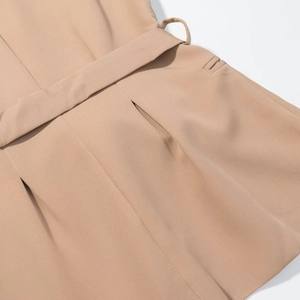 Detailed close-up of khaki sleeveless vest waist featuring belt loops and woven texture