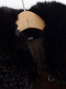 Detailed macro of the fluffy black faux fur collar and matte leather jacket texture