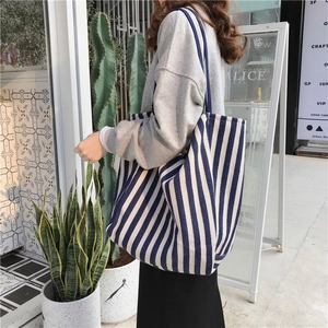 Outdoor shot of a large blue and white striped canvas tote bag worn by a model