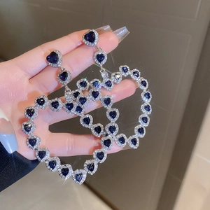 Detailed view of silver hoop earrings with oversized dark blue heart shaped crystals