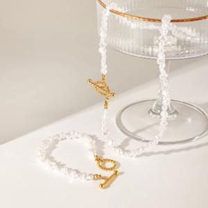 Baroque pearl necklace and bracelet set with 18K gold OT buckle on a glass stand
