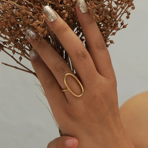 Anello aperto ovale cavo placcato oro 18 carati su mano con elegante sfondo floreale