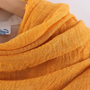 Detailed macro view of orange crinkled cotton linen fabric with soft textured weave