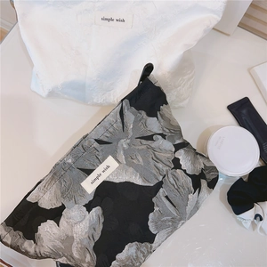 Close-up of black and white floral jacquard makeup bags with zipper and brand label