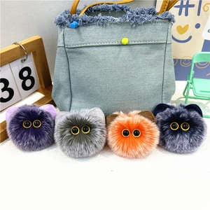 Close-up of fluffy plush cat head keychains in purple, gray, orange and blue colors
