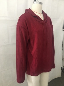 Dettaglio della trama a trecce rosse su una maglia con cappuccio a maniche lunghe