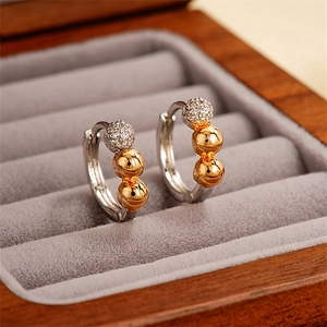 Detailed view of silver hoop earrings with pave-set zircon and golden beads on velvet box