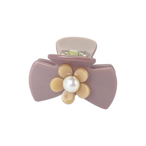 Detail of mauve claw clip with a cream camellia flower and white pearl center