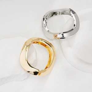 Detailed view of chunky twisted gold and silver bangles on white minimalist stones