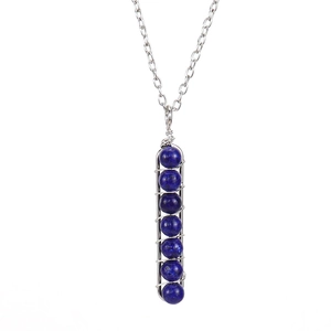 Macro shot of seven blue beads hand-wrapped in silver wire on a long bar pendant