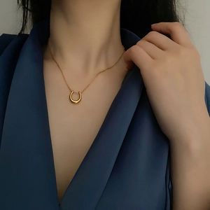 Minimalist gold U-shaped pendant necklace in titanium steel on elegant blue silk fabric
