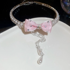 Detailed macro of pink silk bow choker with rhinestone tassels and drop pearls