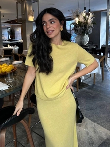 Detail of lime green knitted two-piece set featuring short sleeves and a slim midi skirt