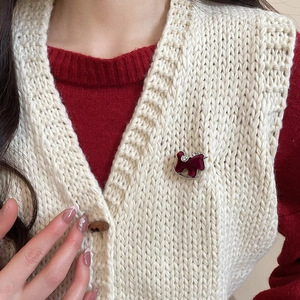 Detail of red flocked rocking horse brooch with rhinestones on white knit sweater