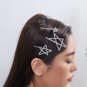 Close-up of three sparkling rhinestone star hair clips styled on model's side hair