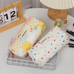 Detail of quilted cotton pencil bags with floral and polka dot patterns in a metal basket