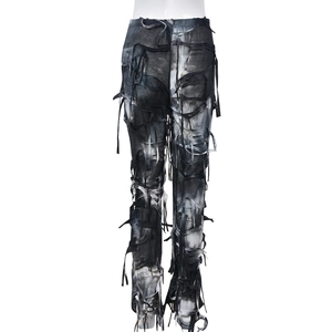 Dettaglio dei pantaloni in denim lavato nero con strappi consumati e accenti di frange