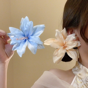 Detail view of large silk fabric lily hair clips in blue and champagne with pearls
