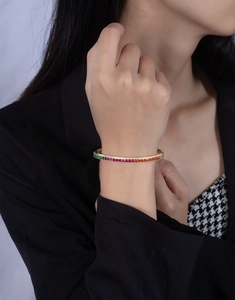Detail of gold-plated silver bangle with rainbow stones worn on a female wrist