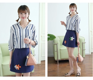 Fashionable pink triangular handbag styled with a striped shirt and embroidered skirt