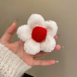 Detail of plush daisy hair claw featuring soft white petals and a red center