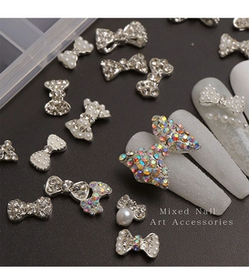 Macro shot of silver bow nail charms with rhinestones and pearls on leather