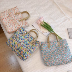 Detail of floral canvas tote bags featuring leather handles and reinforced gold rivets
