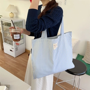 Detail of blue and white striped canvas tote bag showing large capacity and label