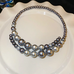 Close-up of double-layered gray pearl necklace featuring alternating sizes on a white plate