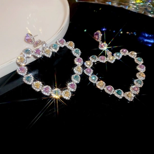 Gros plan de boucles d'oreilles cœur avec zircons colorés et effet scintillant de lumière