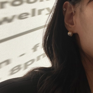 Close-up of elegant pearl earrings with gold base on a female model with soft lighting