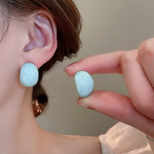 Detail of light blue irregular stone earrings showing marble texture and polished finish