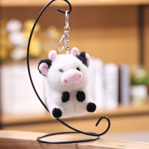 Primer plano de llavero de vaca de peluche en soporte de metal con fondo difuminado