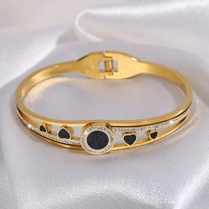 Detailed close-up of golden stainless steel heart bracelet on white silk background