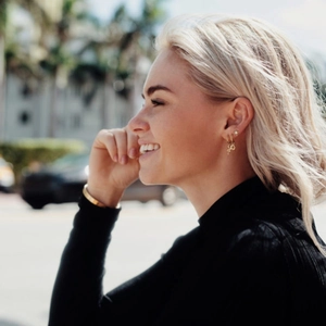 Close-up of a model wearing a gold snake earring and star stud in a stylish street setting