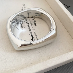 Close-up of a silver minimalist square metal cuff with high-polish mirror finish