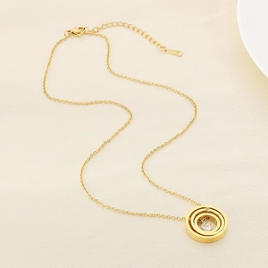 Detail of gold-tone necklace featuring triple-ring pendant with a sparkling zircon inlay