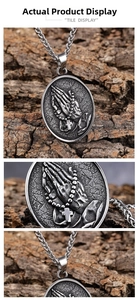 Macro shot of vintage stainless steel oval pendant with praying hands and cross details