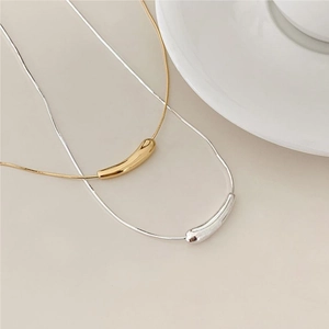 Detailed view of minimalist gold and silver teardrop pendant necklaces on fine snake chains