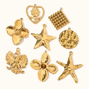 Nine vintage gold titanium steel charms including clover heart and star on white background