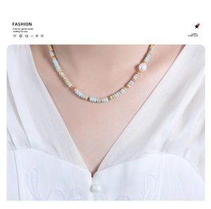 Detail of beaded necklace with light blue round beads and a single freshwater pearl
