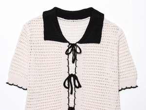 Detail of crochet polo top with black contrast collar and bow ties in beige knit